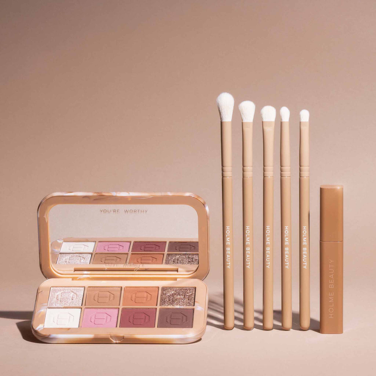 Makeup palette, brushes, and a tube on a beige background