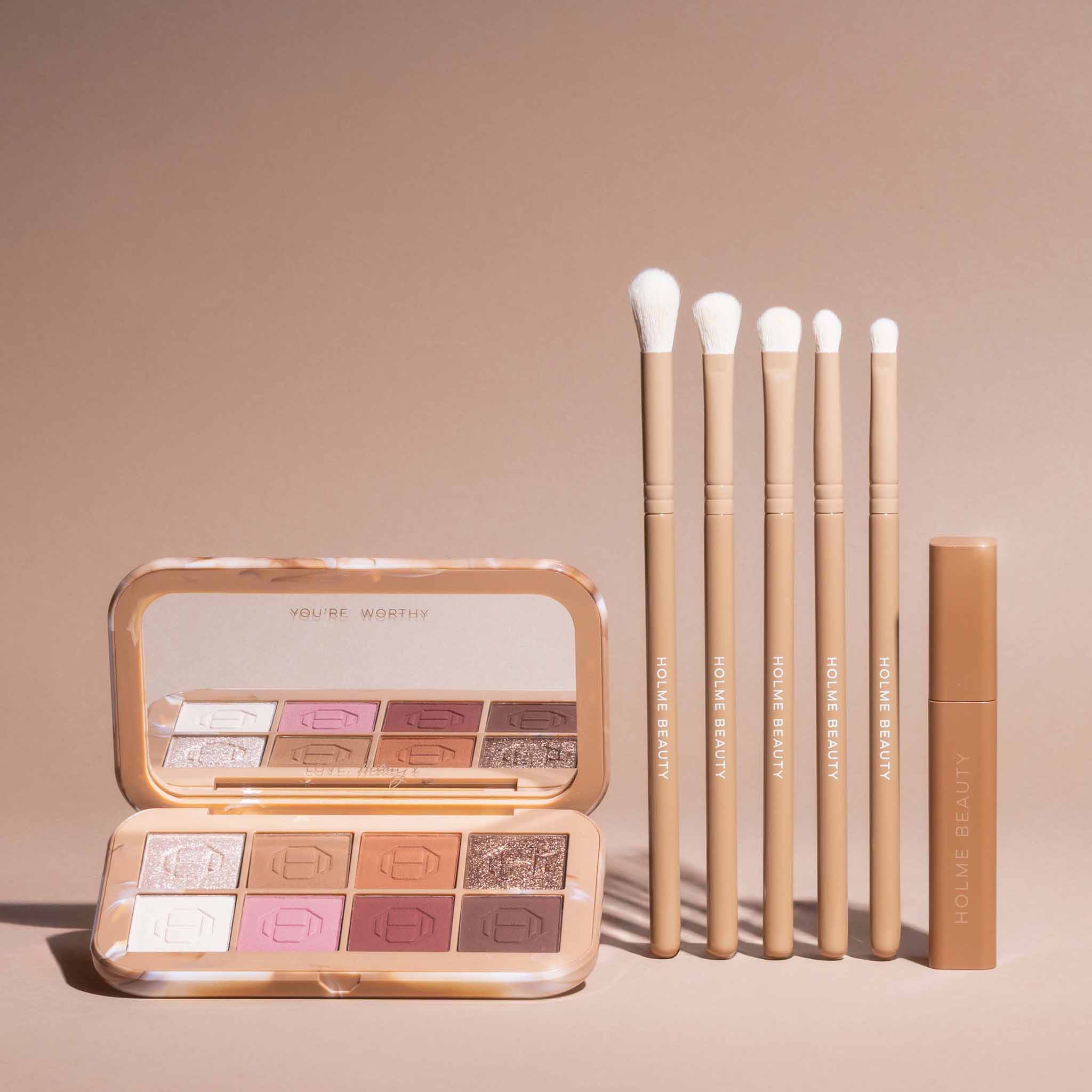 Makeup palette, brushes, and a tube on a beige background