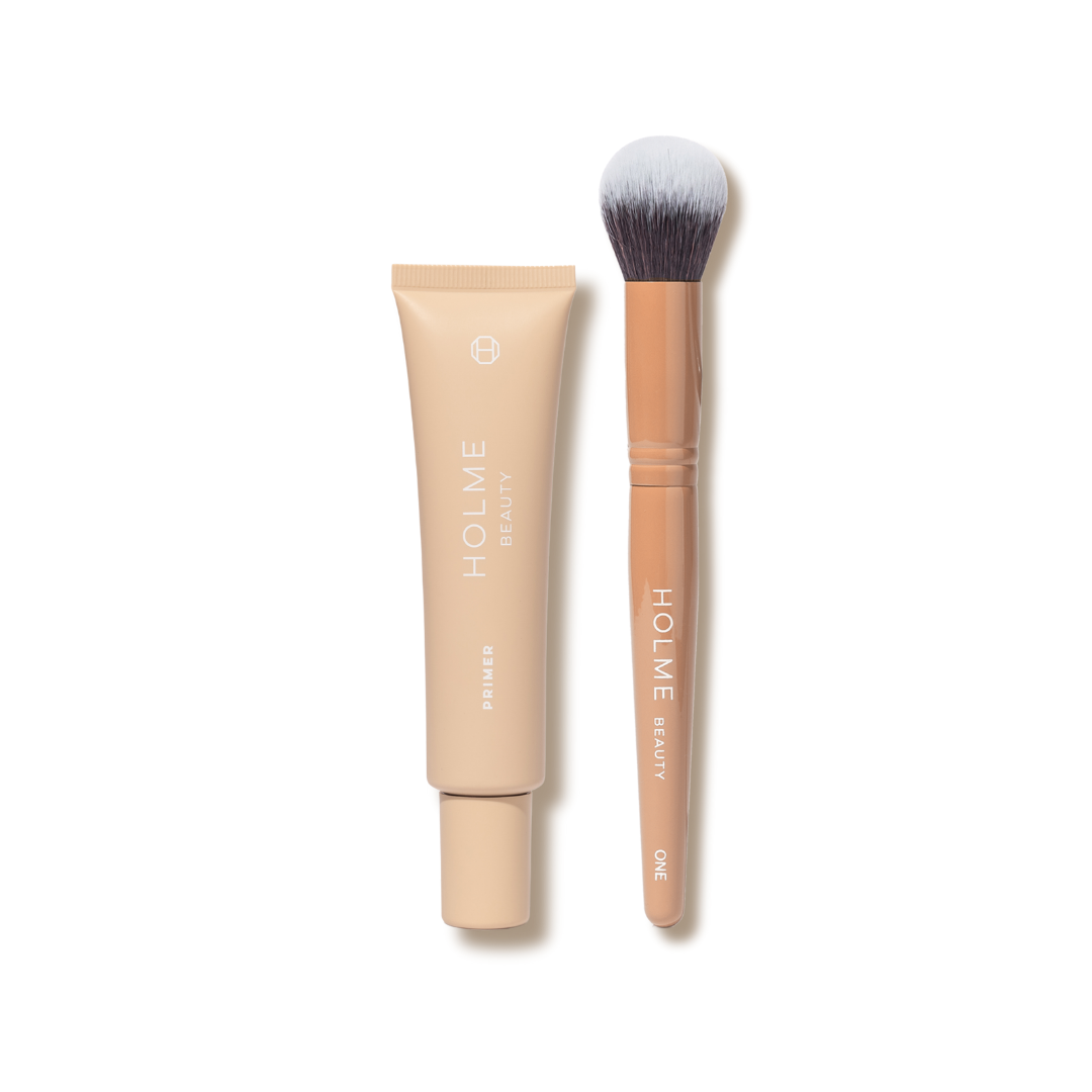 A tube of Holme Base Primer and a Holme Beauty brush, both with beige coloring and branding on the brush handle.